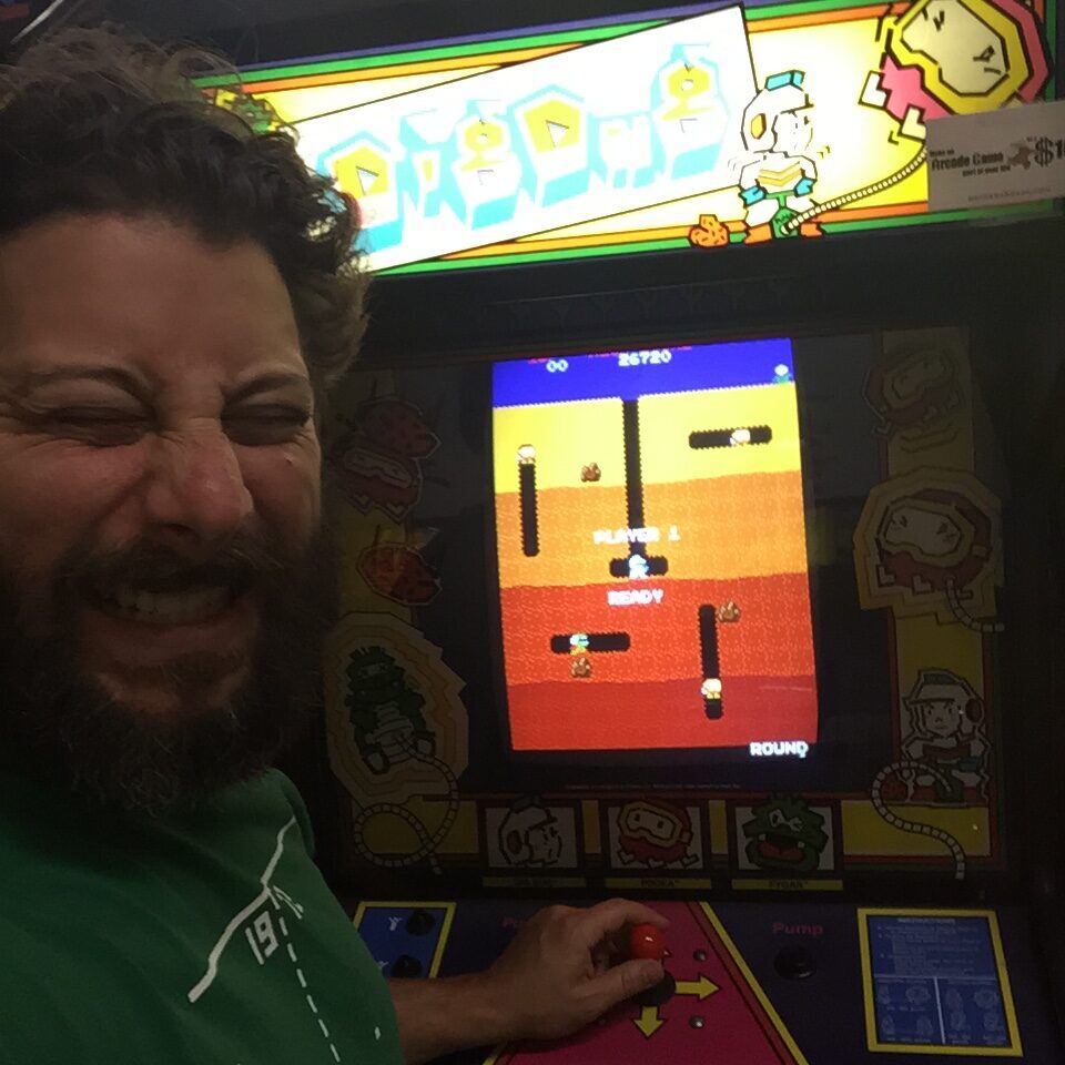 Bryan grinning beside a Dig Dug arcade cabinet